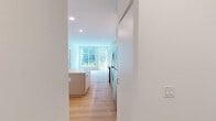 Located at 1529 N Fremont St in Chicago's Lincoln Park neighborhood, this modern 2-bedroom, 3-bathroom residence offers a thoughtfully designed single-level layout finished with light hardwood flooring throughout. The open-concept kitchen and living area anchors the space, featuring sleek flat-front cabinetry in a muted gray tone, white quartz countertops, stainless steel appliances, and a central island that provides additional prep and seating space. Large floor-to-ceiling windows in the living area flood the space with natural light and open to a private balcony with outdoor views. Each bedroom is well-proportioned, with the primary bedroom offering a closet and its own dedicated bathroom. The second bedroom also benefits from generous natural light and a wall-mounted mini-split HVAC unit. All three bathrooms are finished in a consistent modern aesthetic, highlighted by warm wood vanities, matte black fixtures, and distinctive green-and-white checkered tile surrounds in the shower and tub enclosures. Clean white walls and recessed lighting contribute to a bright, contemporary ambiance throughout. The overall design emphasizes minimalism and functionality, making efficient use of the available space.