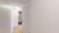 This efficiently designed one-bedroom, one-bathroom unit offers a thoughtful layout that maximizes every square foot of its compact footprint. Light hardwood flooring runs throughout the space, lending warmth and visual continuity across all rooms.

The open living and kitchen area is a standout feature, anchored by expansive floor-to-ceiling windows that frame sweeping panoramic views of the city skyline and distant mountains, flooding the interior with natural light. The kitchen is well-appointed with a full suite of stainless steel appliances, including a refrigerator, electric range, over-the-range microwave, and dishwasher. Sleek two-tone cabinetry — white uppers paired with grey lowers — is complemented by granite countertops and a mosaic tile backsplash, offering a clean, contemporary aesthetic with track lighting above.

The bedroom is a quiet, well-proportioned retreat featuring a sliding-door closet with a built-in hanging rod, crisp white walls, and the same warm hardwood flooring.

The bathroom is finished with large-format dark tile flooring, white subway tile surrounding the soaking tub and shower combination, a floating white vanity with granite countertop, and a large mirror. The overall ambiance throughout the unit is modern, clean, and bright, with a neutral palette that creates a calm and functional living environment.