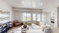 Located in Rathdrum, Idaho, this single-floor residence offers 2 bedrooms, 2 bathrooms, a dedicated office, and a thoughtfully designed open-concept living area. The living room is bright and welcoming, with large windows overlooking an outdoor balcony, recessed lighting, textured ceilings, and light wood-look flooring that flows throughout the main areas. The kitchen is well-equipped with dark espresso cabinetry, white quartz countertops, stainless steel appliances including a refrigerator and range, subway tile backsplash, a deep undermount sink, and pendant lighting — ideal for both everyday cooking and entertaining. The adjacent dining area provides a comfortable, defined space for meals. The spacious primary bedroom features plush carpeting and generous natural light, while the second bedroom and dedicated office offer flexibility for guests or remote work, each with carpet flooring and windows. Both bathrooms are finished with wood-look flooring, clean white fixtures, and a tub-shower combination. The overall design palette is neutral and modern, with soft whites and warm tones creating a cohesive, move-in-ready atmosphere throughout.
