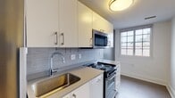 Located at 32 High St in the heart of New Haven, CT, Unit 506 is a well-appointed one-bedroom, one-bathroom apartment that combines modern updates with classic details. The living and bedroom areas feature warm hardwood flooring throughout, complemented by crisp white walls and elegant wall sconce lighting that add a timeless character to the space. Natural light filters in through windows, brightening each room.

The kitchen has been thoughtfully updated with white shaker-style cabinetry fitted with brushed metal hardware, a gray tile backsplash, and quartz-style countertops. Stainless steel appliances — including a built-in microwave, electric range, and dishwasher — along with a modern arc-neck faucet over a stainless steel sink, complete the functional and stylish culinary space. Light tile flooring and a window provide added brightness.

The bathroom is finished with large-format marble-style tile flooring, a clean white vanity with mirror, and a shower/tub combination, all bathed in natural light from a grid-pane window. The overall layout flows efficiently through a central hallway connecting all rooms, offering a practical and comfortable living arrangement in a prime New Haven location.