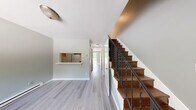 Located at 29 Partridge Hill Rd in Hyde Park, NY, this multi-floor unit spans three levels plus a basement, offering a functional and practical layout throughout. The main floor features light gray wood-look flooring, soft sage-toned walls, and an open hallway leading to a pass-through kitchen. The galley-style kitchen is outfitted with warm oak cabinetry, ample upper and lower storage, a double sink, tile flooring, and white appliances including a refrigerator and electric range. Stairs with a dark wood banister and black metal railing connect each level, adding a classic touch to the interior. The bedrooms are found across the upper floors, each featuring the same light wood-look flooring, neutral tones, and windows that invite natural light. The primary bedroom offers a generous footprint among the three. The two bathrooms feature green ceramic tile wainscoting, a tub-shower combination, and tile flooring. The unfinished basement provides additional utility space and houses the water heater. Outside, a wood deck extends from the unit, offering scenic views of mature trees, open green lawn, and the quiet surrounding neighborhood — an inviting spot to enjoy the natural setting of Hyde Park.