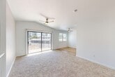 Located at 7511 N 1st St in Fresno, CA, this one-bedroom, one-bathroom unit offers a thoughtfully designed single-floor layout with a staircase entry and efficient use of space throughout. The open living area is highlighted by vaulted ceilings, soft neutral carpeting, and dual ceiling fans that enhance airflow and comfort. A full-width sliding glass door floods the room with natural light while providing direct views of the surrounding greenery, creating a bright and airy atmosphere. The kitchen is well-appointed with gray cabinetry, light quartz-style countertops, a classic tile backsplash, stainless steel appliances including a range and refrigerator, and warm hardwood-style flooring — offering a clean, modern aesthetic. The bedroom is a comfortable retreat featuring plush carpeting, a ceiling fan, a double-door closet, and a window that brings in additional natural light. A second closet area provides extra storage near the hallway. The bathroom is finished with a white subway tile tub surround, a granite-topped vanity, and hardwood-style flooring, maintaining a clean and contemporary feel. Hallways connect the spaces efficiently, completing this well-organized and move-in ready home.