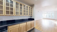 Located in the heart of Downtown Los Angeles at 220 W 5th St, this 1-bedroom, 2-bathroom residence offers a thoughtfully designed single-floor layout with generous living space. The open living areas are defined by warm hardwood flooring, crisp white walls, and soaring ceilings that amplify the sense of volume throughout. Expansive multi-pane windows flood the living room with natural light while framing urban views of the surrounding Downtown skyline and historic brick architecture.

The kitchen is well-equipped and functional, featuring light maple cabinetry with glass-front upper doors, sleek dark granite countertops, stainless steel appliances including a range, dishwasher, and microwave, as well as dark tile flooring. An extended counter area provides additional prep and storage space that connects seamlessly to the living areas.

The spacious primary bedroom offers a calm retreat with hardwood floors and access via a distinctive wood-framed glass door. Both bathrooms are finished consistently with warm beige stone tile floors and walls, a combined tub and shower with glass enclosure, and a vanity featuring light maple cabinetry topped with dark granite. The overall design blends classic Downtown LA character with clean, modern finishes throughout.