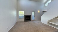 This two-story residence spans 1,340 square feet and offers 4 bedrooms and 2 bathrooms across two thoughtfully laid-out floors. The main level (780 sq ft) centers around a combined kitchen and living room. The living room is a standout space, featuring soaring vaulted ceilings, carpet flooring, a tile-surround fireplace, and multiple windows that bring in natural light. An elegant arched doorway connects the living area to the kitchen, which is equipped with dark espresso cabinetry, white quartz countertops, a tile backsplash, stainless steel appliances, and durable wood-look plank flooring. A full bathroom on the main level includes a shower/tub combo with white tile surround, wood-look flooring, and a dark vanity with a mirrored medicine cabinet. The upper level (560 sq ft) houses the spacious primary bedroom suite, complete with carpet flooring, a walk-in closet featuring built-in shelving, and a private en-suite bathroom. Three additional bedrooms are carpeted and bright, each with windows offering outdoor views. A dedicated hallway and closet add to the home's practical storage and circulation. Throughout the home, neutral white walls and consistent finishes create a clean, cohesive aesthetic.