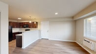 Located at 11103 W Sixth Ave in Airway Heights, Washington, unit C303 is a single-floor residence offering a clean, modern design with a practical and comfortable layout. The open-concept living and dining area is finished with light-toned laminate wood flooring that extends throughout the unit, creating a cohesive and airy feel. Neutral warm-beige walls complement the recessed lighting overhead, while windows allow natural light to fill the space.

The kitchen is well-equipped and thoughtfully designed, featuring rich dark-wood cabinetry with brushed nickel hardware, light granite-style countertops, a double-basin stainless steel sink, and a full suite of black appliances including a refrigerator, electric range, and over-the-range microwave. A breakfast bar with pendant lighting connects the kitchen to the living area, making it ideal for casual dining or entertaining.

The bedroom is a generously sized room with a window that brings in natural light and provides views to the outside. The bathroom includes a granite-topped dark wood vanity with a single sink, a tub-shower combination, and light wood-style flooring. An in-unit washer is also present, adding everyday convenience. The unit presents a move-in-ready, functional living environment in a well-maintained residential setting.
