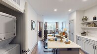 Located at 994 W Second St in Winston-Salem, NC, this well-appointed single-floor residence offers a thoughtfully designed open-concept layout. The kitchen is a standout feature, outfitted with crisp white shaker cabinetry, stainless steel appliances, a herringbone-patterned tile backsplash, and a large center island with light quartz countertops and seating — ideal for casual dining or entertaining. Rich wood-tone luxury vinyl plank flooring runs throughout the main living areas, adding warmth and cohesion to the space. The kitchen flows seamlessly into the living room, which is bathed in natural light from expansive windows with views of surrounding greenery. The bedrooms are comfortably scaled, each with large windows, plush carpet, and ample closet space. The primary suite connects to a well-organized bathroom featuring a shaker-style vanity with dark hardware and direct access to a walk-in closet. Throughout the unit, clean white walls, recessed lighting, and black accent hardware contribute to a consistent modern aesthetic. The overall ambiance is bright, functional, and contemporary, offering a comfortable living environment in a convenient Winston-Salem location.