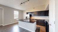 Located at 4115 Britton Pky in Hilliard, Ohio, this single-floor residence offers a thoughtfully designed layout that maximizes functionality and style. The open-concept kitchen serves as the heart of the home, showcasing a large center island with dark granite countertops and an integrated sink, complemented by rich espresso-toned cabinetry, subway tile backsplash, and a full suite of stainless steel appliances including a French door refrigerator, electric range, built-in microwave, and dishwasher. Track lighting overhead adds a modern touch, while a nearby window fills the space with natural light. Hardwood flooring flows throughout the main living areas, lending warmth and continuity. The living area features a bank of three windows, flooding the room with abundant natural light and offering pleasant outdoor views. The bedroom is a comfortable retreat with its own window framing outdoor scenery and direct access to a spacious walk-in closet equipped with wire shelving systems. The bathroom includes a vanity with under-sink storage, a large mirror, and tile flooring. A sliding barn door leads to an additional utility area, completing this efficiently designed Hilliard residence.