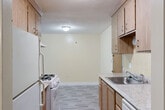 This one-bedroom, one-bathroom unit in Lynn, MA offers a practical and functional single-floor layout. The galley-style kitchen is efficiently designed with light wood cabinetry extending to the ceiling for ample storage, a stainless steel sink, laminate countertops, and wood-look plank flooring. It is equipped with a gas range and refrigerator, with a dishwasher also included. The kitchen opens toward a combined living and dining area, creating a connected and versatile living space with neutral walls that invite personalization. The bedroom is generously proportioned, featuring soft carpeting, baseboard heating, a large window that brings in natural light with views of the surrounding neighborhood, and two closets — including a sliding-door double closet — providing excellent storage. The full bathroom features a classic white subway tile surround around a full soaking tub. A hallway connects the main living areas and includes access to additional storage. The building itself is a brick exterior structure with an on-site parking lot. The warm, neutral color palette throughout the unit creates a clean and move-in ready environment.