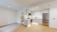 Located at 163 Willoughby Street in the heart of Downtown Brooklyn, this thoughtfully designed studio unit offers a compact yet highly functional single-floor layout. The open-plan living and kitchen area is anchored by striking herringbone-patterned hardwood floors that run throughout, adding warmth and visual interest to the bright, white-walled interior. Recessed lighting and a large black-framed window flood the living space with natural light, offering views of the surrounding urban streetscape.

The kitchen is outfitted with sleek, floor-to-ceiling white cabinetry, white quartz countertops, and stainless steel appliances including a multi-door refrigerator and a professional-grade range with hood. Under-cabinet lighting adds a refined finishing touch, while the clean-lined hardware and minimalist design give the kitchen a contemporary, polished feel.

The bathroom showcases a distinct spa-inspired aesthetic, featuring terrazzo-style tile flooring, vertically textured wall tiles, and warm wood accents. A bamboo-finish floating vanity, a frameless glass-enclosed tub and shower, and a pendant light overhead complete the serene, well-curated design. Together, these spaces deliver a modern, urban living experience in one of Brooklyn's most vibrant neighborhoods.