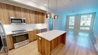 Located at 400 W Swedesford Rd in Berwyn, PA, this well-appointed two-bedroom, two-bathroom residence offers a thoughtfully designed single-floor layout. The open-concept kitchen and living area serves as the heart of the home, featuring warm wood-grain cabinetry, a large center island with a crisp white quartz countertop, stainless steel appliances including a french door refrigerator and range, and stylish glass pendant lighting. Light hardwood-style flooring flows throughout the main living area, which is bathed in natural light from large windows overlooking lush outdoor greenery. A private exterior door provides convenient outdoor access directly from the living space. Both bedrooms are carpeted and generously sized, each offering multiple windows that frame peaceful tree-lined views. The primary bedroom includes a dedicated closet outfitted with wire shelving systems for organized storage. The two bathrooms are finished with clean, neutral tile work — one featuring a glass-enclosed walk-in shower and the other a soaking tub with subway tile surround. A hallway connects the living spaces to the bedrooms, maintaining a functional and efficient floor plan throughout this comfortable Berwyn residence.