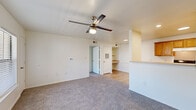 This 2-bedroom, 1-bathroom residence is laid out on a single floor, offering a practical and cohesive living environment. The combined kitchen and living room serves as the heart of the home, with the living area featuring neutral-toned carpet, bright white walls, and a ceiling fan with light fixture. A built-in shelving nook and desk area add functional character to the space.

The galley-style kitchen is equipped with warm oak cabinetry lining both sides, light countertops, a white electric range, a full-size refrigerator, and a stainless steel sink. Light wood-style flooring runs throughout the kitchen, providing a clean contrast to the carpeted living areas.

Both bedrooms are carpeted and feature ceiling fans, windows with horizontal blinds that allow natural light, and a comfortable, quiet ambiance. The primary bedroom offers a modest but practical footprint, while the second bedroom includes a window with an outdoor view.

The bathroom is clean and functional, featuring a full-size tub and shower combination, a wood-toned vanity with a sink, and light wood-style flooring. A walk-in closet with wire shelving is accessible directly from the bathroom, providing convenient storage.

Overall, this residence presents a straightforward, well-maintained layout suited for comfortable everyday living.