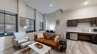 Located on Euclid Avenue in the heart of Cleveland, OH, this thoughtfully designed one-bedroom, one-bathroom unit offers a well-organized layout across a single floor. The open-concept living and kitchen area forms the centerpiece of the space, characterized by soaring ceilings and large steel-framed windows that flood the room with natural light and offer views of the surrounding urban streetscape. Light wood-look flooring runs throughout the main living areas, complementing the neutral, modern palette.

The kitchen is fully equipped with dark espresso cabinetry, stainless steel appliances including a range, microwave, dishwasher, and refrigerator, as well as a decorative tile backsplash that adds texture to the space. A dedicated dining area sits adjacent, making the combined kitchen and living room ideal for both everyday living and entertaining.

A clean hallway connects the main living area to the private quarters, featuring a circular wall mirror and louvered closet doors. The bedroom offers plush carpeting, high ceilings, a walk-in closet, and a direct entrance to the bathroom. The full bathroom includes wood-look tile flooring, a dark vanity with a stone-look countertop, and a tiled walk-in shower. An in-unit laundry area and two closets add practical storage and convenience to this efficiently designed urban residence.