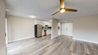 This single-floor residence offers a thoughtfully updated interior with a cohesive, modern design. The open-concept living and dining area is anchored by light-toned luxury vinyl plank flooring and a stylish gold ceiling fan, creating a bright and welcoming atmosphere. A fireplace with a classic surround adds character to the living space, which also benefits from a large window that invites natural light.

The kitchen is a standout feature, showcasing white shaker-style cabinetry, light quartz countertops, and a teal subway tile backsplash that adds a pop of color. A full suite of stainless steel appliances — including a refrigerator, range, microwave, and dishwasher — completes the functional and attractive cooking space.

The bedrooms are finished with soft wall-to-wall carpeting and neutral walls, providing a comfortable and quiet retreat. Each room is well-proportioned, with windows offering outdoor views. The bathroom is finished with clean white subway tile surrounding a full soaking tub and shower, fitted with chrome fixtures for a crisp, polished look.

Throughout the space, textured ceilings, white trim, and a neutral color palette tie the rooms together, delivering a clean and move-in-ready environment suitable for everyday living.