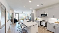 Located in Leander, TX, this thoughtfully designed one-bedroom, two-bathroom residence offers an efficient and modern layout. The open-concept kitchen and living area serves as the heart of the home, anchored by a large white quartz island with an integrated sink and bar seating — ideal for casual dining or entertaining. The kitchen is outfitted with gray shaker-style cabinetry, a classic subway tile backsplash, stainless steel appliances including a range, microwave, and refrigerator, and light wood-look flooring that extends throughout the main living areas. The living room is bright and welcoming, featuring large windows with horizontal blinds and sheer curtains, a ceiling fan, and access to an outdoor balcony that brings in generous natural light. The bedroom is a calm retreat finished with plush carpet, a ceiling fan, and a sizable window with outdoor views. A walk-in closet with built-in shelving and dual hanging rods provides practical storage. The bathrooms include a soaking tub with a tiled surround and a curved shower rod. Clean white walls, recessed lighting, and a neutral color palette throughout give the space a cohesive, contemporary feel.