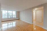 Located at 195 Kennedy Rd S in Brampton, Ontario, this 2-bedroom, 1-bathroom unit offers a practical and well-laid-out living space. The interior is unified by warm-toned parquet flooring that extends throughout the living areas and bedrooms, lending a classic character to the home.

The combined living and dining area is generously proportioned, highlighted by large floor-to-ceiling windows that flood the space with natural light and offer views of the surrounding neighbourhood. A baseboard heating system runs along the window wall, ensuring comfortable year-round living.

The kitchen is thoughtfully appointed with white cabinetry, dark granite-style countertops, a subway tile backsplash, stainless steel appliances including a refrigerator and electric range, and clean tile flooring. An open passageway connects the kitchen directly to the living area for easy flow.

Both bedrooms continue the parquet flooring theme. The primary bedroom includes a closet and direct access to the full bathroom, while the second bedroom features a window with an outdoor view and a closet. The bathroom is clean and functional, featuring a full soaker tub with white tile surround. A hallway connects all rooms efficiently, completing this well-organized and move-in-ready home.