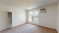 Located at 3545 Mather Field Rd in Rancho Cordova, CA, this one-bedroom, one-bathroom unit offers a practical and efficient single-floor layout. The living room is carpeted and bathed in natural light through a large sliding window fitted with vertical blinds, offering views of surrounding greenery. A wall-mounted heater provides in-unit climate control, complementing the wall-unit air conditioner found in the bedroom. The bedroom is a comfortable, well-proportioned space with plush carpeting, a large window with vertical blinds, and its own wall-mounted AC unit for independent temperature control. Two closets offer ample storage throughout the unit. The galley-style kitchen features warm wood cabinetry, light countertops, a stainless steel sink, and light wood-look vinyl flooring, with space for a range and dishwasher. A dedicated dining area adjoins the kitchen for convenient meal times. The bathroom is finished with light vinyl flooring, a wood-cabinet vanity topped with a speckled countertop and a large mirror, plus a full bathtub and shower. A hallway connects the main living areas, completing this well-organized and functional floor plan.