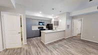 This single-story 2-bedroom, 2-bathroom unit offers a thoughtfully designed open-concept layout connecting the kitchen and living area. The kitchen is outfitted with sleek gray cabinetry, quartz-style countertops, black appliances including a range, microwave, and refrigerator, and a peninsula with a built-in sink — ideal for both meal prep and casual dining. Stylish pendant lighting accents the space, and wood-look flooring runs consistently throughout the entire unit, lending a cohesive and modern aesthetic.

The living area is generously sized, featuring a ceiling fan, neutral-toned walls, and natural light from blinds-covered windows. Both bedrooms are well-proportioned, bright, and share the same warm, neutral palette and durable flooring. The primary bedroom includes its own closet with built-in shelving and hanging rods for ample storage.

Each bathroom features a gray vanity with white countertop, a walk-in shower, and overhead lighting with a large mirror. The dedicated laundry room includes overhead gray cabinetry matching the kitchen, washer and dryer hookups, and a utility sink connection. A separate utility room and additional closets round out the functional layout of this clean, move-in-ready space.
