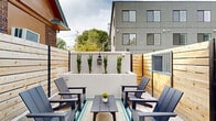 Located at 11 Merrimac Ave in Salt Lake City, Utah, this one-bedroom unit is part of a modern multi-unit building that blends contemporary design with inviting outdoor amenities. The interior showcases warm, natural tongue-and-groove wood paneling that covers both the walls and ceiling, creating a cozy, cabin-like atmosphere with rich grain detail throughout.

The building's exterior is finished in a sleek gray facade with large multi-pane windows, offering a clean, modern aesthetic. Residents benefit from thoughtfully designed shared outdoor areas, including a fully enclosed courtyard patio furnished with Adirondack-style chairs, a central coffee table, and a striped area rug, accented by vertical evergreen shrubs and string lighting for a welcoming atmosphere. A lush artificial turf corridor runs alongside the building, bordered by horizontal cedar fencing and classic black lantern-style wall sconces.

Secure access is provided via a large charcoal-colored metal gate with an X-brace design, opening to a spacious concrete driveway. The property also includes a dedicated pet wash station, adding everyday convenience for residents. Situated in a neighborhood surrounded by mature trees and with views of the surrounding Salt Lake Valley, this unit offers a compact yet character-rich living experience.