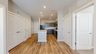 Located at 565 Cobb Pkwy S in Marietta, GA, this single-floor, 2-bedroom, 2-bathroom unit offers a thoughtfully designed layout with modern finishes throughout. The open-concept kitchen is a standout feature, showcasing dark gray shaker-style cabinetry extending to the ceiling, light countertops, black appliances including a refrigerator, range, microwave, and dishwasher, and a central island that provides additional prep and seating space. Wood-look luxury vinyl plank flooring runs through the kitchen and main living areas, adding warmth and continuity to the space. The living area is bright and functional, enhanced by a ceiling fan and natural light from windows with blinds. Both bedrooms are carpeted and include ceiling fans, with natural light filtering in through multiple windows. The primary bedroom connects to a dedicated closet with built-in shelving and an adjoining bathroom. Each bathroom features wood-look flooring, a dark-toned vanity with light countertops, and a tub-shower combination. Two closets throughout the unit offer practical storage solutions. The overall aesthetic is clean and contemporary, with a neutral color palette that creates a cohesive and inviting atmosphere across every room.
