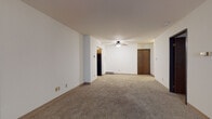 Located at 933 N Marshall St in Milwaukee's vibrant East Side neighborhood, this single-floor unit offers a practical and well-organized layout. The spacious main living area features neutral wall-to-wall carpeting, white walls, and a ceiling fan with light fixture, creating a comfortable and adaptable space. A large picture window in an adjacent room floods the area with natural light and includes a built-in carpeted bench beneath it, adding a distinctive architectural touch.

The kitchen is efficiently designed with warm honey-toned cabinetry, dark granite-style countertops, a black electric range with overhead ventilation, a black refrigerator, and tile flooring — offering ample storage and workspace. The bedroom is generously sized with carpeted flooring, a window with blinds, and a wall-mounted HVAC unit for climate control.

The unit includes two bathrooms: one featuring a tiled tub-shower combination with a vanity and tile flooring, and a second with a tiled walk-in shower, also with a vanity and tile flooring. Adjacent to the second bathroom is a convenient in-unit stacked washer and dryer. A hallway connects the bedroom to the bathrooms, with closet access for additional storage. The overall layout is functional, clean, and move-in ready.