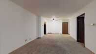 Located at 933 N Marshall St in Milwaukee's vibrant East Side neighborhood, this single-floor unit offers a practical and well-organized layout. The spacious main living area features neutral wall-to-wall carpeting, white walls, and a ceiling fan with light fixture, creating a comfortable and adaptable space. A large picture window in an adjacent room floods the area with natural light and includes a built-in carpeted bench beneath it, adding a distinctive architectural touch.

The kitchen is efficiently designed with warm honey-toned cabinetry, dark granite-style countertops, a black electric range with overhead ventilation, a black refrigerator, and tile flooring — offering ample storage and workspace. The bedroom is generously sized with carpeted flooring, a window with blinds, and a wall-mounted HVAC unit for climate control.

The unit includes two bathrooms: one featuring a tiled tub-shower combination with a vanity and tile flooring, and a second with a tiled walk-in shower, also with a vanity and tile flooring. Adjacent to the second bathroom is a convenient in-unit stacked washer and dryer. A hallway connects the bedroom to the bathrooms, with closet access for additional storage. The overall layout is functional, clean, and move-in ready.