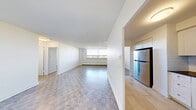 Located at 2570 Kingston Rd in Toronto's Kingston Road corridor, this 2-bedroom, 1-bathroom unit offers a well-organized layout across a single floor. The open living area is generously sized, featuring classic parquet flooring throughout and crisp white walls that create a clean, bright atmosphere. A large window in the main living space allows natural light to pour in while offering outward views, complemented by a baseboard heating unit beneath.

The kitchen has been thoughtfully renovated with white shaker-style cabinetry, dark countertops, a subway tile backsplash, and light tile flooring. It is equipped with a full suite of stainless steel appliances, including a refrigerator, stove, over-the-range microwave, and dishwasher, providing a fully functional and modern cooking space.

The spacious primary bedroom features the same parquet flooring, neutral walls, and a set of built-in sliding-door closets offering ample storage. The second bedroom is also well-proportioned and bright, with access to additional closet space. The bathroom is finished with large-format floor tiles, white subway tile surrounding the soaker tub and shower combination, and clean white fixtures. A dedicated closet rounds out the unit's practical storage offerings.