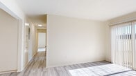 Located at 5600 Orangethorpe Ave in La Palma, CA, this 2-bedroom, 1-bathroom single-floor unit offers a clean, functional layout with a bright and neutral aesthetic throughout. Light-toned luxury vinyl plank flooring runs consistently across every room, lending a cohesive, modern feel to the space.

The living room is a welcoming area featuring a ceiling fan with light fixture and a sliding glass door dressed with vertical blinds, allowing generous natural light and outdoor views of surrounding palm trees. A wall-mounted HVAC unit provides climate control.

The kitchen is efficiently laid out with tall cream cabinetry offering ample storage, a range with overhead exhaust hood, and warm wood-toned countertops. Recessed ceiling trim details add a subtle decorative touch.

The primary bedroom is generously sized and includes a full-width built-in closet with sliding doors and integrated shelving, maximizing storage. The second bedroom also includes a dedicated closet and connects conveniently to the hallway.

The bathroom is well-appointed with a single-sink vanity featuring under-sink cabinetry, a large mirror, and a shower-tub combination with sliding glass doors.

A connecting hallway with overhead lighting ties the layout together, providing smooth flow between all rooms. The unit's consistent finishes and abundant natural light create a clean, move-in-ready environment.