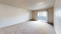 Located at 2000 East River Road in Tucson, AZ, this two-bedroom, three-bathroom residence offers a functional and comfortable single-floor layout. The living room is a generously carpeted space featuring a textured ceiling, baseboard heating, and a sliding glass door that opens to a private outdoor area, allowing natural light to fill the room. Adjacent to the living area, the galley-style kitchen is well-appointed with warm wood-toned cabinetry extending to the ceiling, white appliances including a range and dishwasher, a stainless steel sink with white countertops, and wood-look flooring beneath a skylight panel that brightens the space.

The two bedrooms are carpeted and feature textured ceilings, baseboard heaters, and windows that bring in outdoor light. The primary bedroom is spaciously proportioned with ample room for furnishings. The three bathrooms include a combination tub/shower with white tile surround, a separate walk-in shower with a white surround and wood-look flooring, and a vanity area with a wide white countertop, under-sink cabinetry, and a lighted mirror. A hallway with built-in shelving adds convenient storage, complementing a dedicated closet elsewhere in the unit. The overall aesthetic is clean, neutral, and move-in ready.