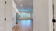 Located at 1425 Gallatin Pike N in Nashville, TN, this single-floor unit offers a thoughtfully designed open-concept layout that seamlessly blends the kitchen and living areas into one cohesive space. Light wood-tone vinyl plank flooring runs throughout, complementing the bright white walls and recessed lighting that create a clean, modern aesthetic. A ceiling fan anchors the living area, which receives natural light through large windows fitted with horizontal blinds, offering views of the surrounding exterior.

The kitchen is a standout feature, showcasing crisp white shaker-style cabinetry with gold-accented hardware, a herringbone tile backsplash, and granite countertops. A full suite of stainless steel appliances — including a French door refrigerator, electric range, over-the-range microwave, and dishwasher — complete the space with a polished, functional feel. A black matte single-basin sink with a window nearby adds practicality and charm.

The bathroom continues the refined design language, featuring light-toned tile flooring, white cabinetry with gold hardware, a granite-topped vanity, and matte black fixtures and grab bars. Paneled white doors with black hardware are used consistently throughout, tying the overall design together with a contemporary yet timeless look.