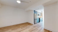 This well-appointed 2-bedroom, 3-bathroom residence showcases a clean, contemporary design defined by crisp white walls, light-toned hardwood flooring, and black-accented fixtures that run consistently throughout the space. The open living area connects seamlessly to a galley-style kitchen, which features a dual-tone cabinetry scheme pairing slate-blue lower cabinets with warm wood upper shelving, complemented by white quartz countertops and a full suite of stainless steel appliances including a gas range, built-in microwave, refrigerator, and dishwasher. Both bedrooms are generously proportioned, bathed in natural light through large black-framed windows that frame outdoor views of the surrounding neighborhood. One bedroom opens directly to a private outdoor balcony through a floor-to-ceiling sliding glass door, while the other features a dedicated closet with built-in shelving. Additional storage is provided by a spacious walk-in closet. All three bathrooms are finished with large-format neutral tile, light wood vanities with white quartz countertops, and matte black hardware. Hallways connect the rooms in a logical, efficient layout, and a dedicated closet adds further practicality. The overall ambiance is bright, minimal, and move-in ready.