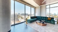 Located at 622 8th Ave in Nashville, TN, this sophisticated high-rise space offers a compelling blend of modern design and urban panoramas. Floor-to-ceiling curtain-wall glazing dominates the interior, flooding the space with natural light while framing sweeping views of the Nashville skyline and surrounding cityscape. Large-format slate-toned tile flooring runs throughout, lending a refined, cohesive aesthetic.

The main living area features warm wood-accented ceiling detailing and accommodates generous lounge-style seating, with curated furnishings that complement the contemporary design. A formal conference or dining area is positioned at the corner of the building, benefiting from wraparound floor-to-ceiling windows that deliver unobstructed, multi-directional city views.

The gourmet kitchen is outfitted with custom wood cabinetry, stainless steel double wall ovens, a large marble-topped island clad in veined tile, and mirrored backsplash detailing beneath globe pendant lighting in brushed gold.

The rooftop terrace is a standout feature, offering open-air seating areas, raised garden planters with lush greenery, string lighting, and glass-panel railings that preserve unobstructed views of the Nashville skyline—creating a dynamic outdoor extension of the interior.