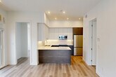Located at 10015 113 St NW in Edmonton's vibrant Oliver neighbourhood, this thoughtfully designed two-bedroom, two-bathroom unit offers a clean, contemporary aesthetic throughout. Light-toned hardwood-style flooring flows seamlessly across the open-concept living and kitchen areas, creating a bright and cohesive feel.

The kitchen is a standout feature, showcasing tall two-tone cabinetry — crisp white uppers paired with rich dark wood lowers — complemented by a striking veined quartz waterfall island and countertops. Stainless steel appliances, including a built-in microwave, electric range, and full-size refrigerator, complete this modern culinary space with under-cabinet lighting adding a refined finishing touch.

Both bathrooms are finished with large-format marble-look porcelain tile on the floors and walls, lending a luxurious feel. The bathrooms feature dark wood vanities with white countertops; one includes an LED-backlit mirror and a glass-enclosed shower, while the other offers a full soaker tub.

The bedrooms are bright and functional, with clean white walls, ample closet space, and light hardwood-style flooring. A dedicated in-suite laundry area with stacked washer and dryer adds everyday convenience. The private balcony offers open views of the Edmonton skyline, rounding out this well-appointed urban residence.
