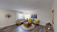 This single-floor residence offers a thoughtfully designed layout across two bedrooms and two bathrooms. The spacious living room serves as the heart of the home, featuring dark hardwood-style flooring, a textured ceiling, and a large window that invites natural light throughout the space. Neutral gray walls provide a versatile backdrop, complemented by clean white baseboards throughout.

The kitchen is outfitted with white shaker-style cabinetry, a gray subway tile backsplash, stainless steel appliances including a refrigerator, range, and microwave, and light quartz countertops. A stacked washer and dryer unit is conveniently integrated into the kitchen area.

The primary bedroom is a well-sized retreat featuring hardwood-style flooring, a large window with blinds, a closet, and neutral tones throughout. The second bedroom also offers a closet and consistent flooring. Both bathrooms feature white vanities with quartz countertops, undermount sinks, and chrome fixtures. A hallway connects the bedrooms and bathrooms, creating an efficient and functional floor plan suitable for everyday living.