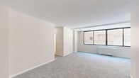 Located at 4500 Connecticut Ave NW in Washington, DC, this one-bedroom, one-bathroom unit offers a functional and well-organized layout across a single floor. An entry hallway welcomes you into the space and leads to the main living area, which features soft wall-to-wall carpeting, neutral tones, and a large window that fills the room with natural light and provides views of the surrounding neighborhood. The open feel of the living area is complemented by clean white walls and generous proportions. The galley-style kitchen is efficiently designed with warm honey-toned wood cabinetry both above and below the countertops, light tile flooring, and white appliances including a gas range and full-size refrigerator, offering ample storage and prep space. The spacious bedroom is carpeted and features dual closets with bifold doors, multiple windows with blinds for natural light and privacy, and a baseboard heating unit. The bathroom includes a full soaking tub and shower combination framed by classic cream-toned square tile, with a window allowing natural ventilation. Throughout the unit, a consistent neutral color palette and practical finishes create a clean, move-in-ready atmosphere well-suited for comfortable urban living.