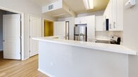 This 420 square foot apartment in Berkeley, CA offers a thoughtful layout maximizing space efficiency. The modern kitchen is a standout feature, boasting crisp white cabinetry extending to the ceiling for optimal storage. Stainless steel appliances, including a full-sized refrigerator, range, and over-the-range microwave, complement the clean aesthetic. A kitchen peninsula adds extra counter space and defines the cooking area.

The 120 square foot bedroom comfortably accommodates a full-sized bed and features a large window allowing natural light to brighten the space. Built-in closets with sliding doors provide ample storage without intruding on the room's footprint. Throughout the apartment, warm-toned hardwood flooring creates a cohesive look and adds a touch of elegance.

The open floor plan allows for a seamless flow between living areas, making the space feel larger than its actual square footage. The neutral color palette, predominantly whites and light grays, further enhances the sense of spaciousness and provides a blank canvas for personal decorating styles.