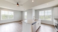 Located on Founder's Lane in Lebanon, Ohio, this single-floor, 2-bedroom, 2-bathroom home offers a thoughtfully designed layout with modern finishes throughout. The open-concept kitchen and living area serves as the heart of the home, featuring warm wood-look flooring, vaulted ceilings, and abundant natural light from large windows with views of surrounding greenery. The kitchen is well-equipped with white shaker cabinetry, granite countertops, stainless steel appliances, and a central island with a sink — ideal for both cooking and casual dining.

The primary bedroom is a comfortable retreat, complete with soft carpeting, generous wall space, and direct access to an en-suite bathroom. The en-suite features white cabinetry, a granite-topped vanity with an undermount sink, and wood-look flooring. The second bedroom also offers plush carpet and a sliding-door closet, providing practical storage. A dedicated walk-in closet with wire shelving adds further organizational convenience.

The second bathroom mirrors the refined finishes seen throughout the home. A dedicated laundry room houses a full-size washer and dryer with overhead wire shelving. Neutral gray walls and consistent flooring tie the entire space together, creating a clean, cohesive, and move-in-ready atmosphere.