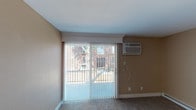 Located at 5107 Colerain Ave in Cincinnati, Ohio, this single-floor unit offers a functional and well-appointed layout. The living area is generously sized, featuring neutral-toned carpet, a sliding glass door with vertical blinds that invites natural light and provides outdoor views, and a wall-mounted air conditioning unit for year-round comfort. The kitchen is a standout space, outfitted with dark espresso cabinetry, stainless steel appliances including a refrigerator and electric range, a marble-style countertop, an undermount sink, and light wood-look flooring that adds warmth and contrast. The bedrooms are carpeted and finished with warm beige walls, ceiling fans with integrated lighting, and individual wall units for climate control. One bedroom includes a sliding closet with double hanging rods, while both rooms feature windows with blinds that allow natural light. A baseboard heating system runs along the perimeter of the bedrooms. The bathroom is cleanly finished with large-format gray tile surrounding the tub-shower combination, coordinating floor tile, and a window for natural ventilation. Throughout the unit, white trim and doors provide a crisp, consistent finish that complements the warm neutral palette.