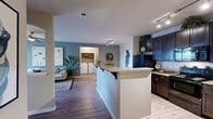 This thoughtfully designed 2-bedroom, 2-bathroom residence offers a comfortable and functional single-floor layout. The open-concept kitchen and living area serves as the heart of the home, featuring rich dark cabinetry, granite-style countertops, black appliances, and a breakfast bar peninsula — all complemented by light hardwood-style flooring. The kitchen flows seamlessly into the dining and living areas, where a bold accent wall in muted blue adds character. The living room is bathed in natural light from a sliding glass door that opens to a private balcony with outdoor views. A ceiling fan adds comfort overhead. The primary bedroom is a serene retreat with plush carpeting, a ceiling fan, and direct access to a walk-in closet. The en-suite bathroom features a vanity with ample counter space and a shower/tub combination. The second bedroom is generously sized with carpet flooring and a ceiling fan, conveniently located near the second full bathroom, which also includes a tub/shower and a single-sink vanity. A dedicated in-unit laundry area with a side-by-side washer and dryer adds everyday convenience. Two closets provide ample storage throughout the residence, completing this practical and stylish home.