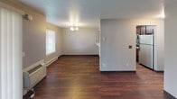 Located at 777 E Magnesium Rd in Spokane, WA, this two-floor residence offers a well-organized layout with distinct living spaces spread across both levels. The main living area features rich, dark hardwood flooring that extends throughout, complemented by a textured ceiling and a charming chandelier that adds a classic touch. A baseboard heating system and a wall-mounted air conditioning unit ensure year-round comfort. Natural light filters in through blinds-equipped windows, creating a bright and inviting atmosphere.

The kitchen is thoughtfully designed with an open pass-through bar topped with a striking marble-style countertop, providing both functionality and visual appeal. Dark espresso cabinetry lines the kitchen walls, paired with a tile backsplash and stainless steel appliances, including a range, microwave, and refrigerator.

The bedrooms are carpeted in warm neutral tones, offering a cozy feel. At least one bedroom includes a walk-in closet, providing ample storage. The bathrooms feature light tile flooring, dark wood vanities with clean white countertops, well-lit mirrors, and practical grab bars, combining style with accessibility. A staircase connects the two floors, making this a cohesive and functional multi-level living space.