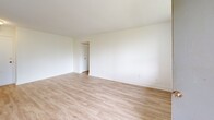 Located at 30 High St E in Mississauga's vibrant Port Credit neighbourhood, this two-bedroom, one-bathroom unit offers a clean, modern aesthetic throughout. Light wood-tone flooring flows seamlessly across every room, complemented by crisp white walls and white trim that create a bright, airy atmosphere.

The combined kitchen and living area serves as the heart of the unit. The kitchen is well-appointed with white shaker-style cabinetry, dark countertops, a stainless steel sink, and includes a refrigerator and range. Natural light enters through a large window that frames views of the surrounding greenery and cityscape.

Both bedrooms are comfortably sized with large windows admitting generous natural light. The primary bedroom features a built-in sliding-door closet, while the second bedroom offers open closet access. Baseboard heating units are present in each room. A private balcony extends from the living area, overlooking lush green lawns and neighbouring buildings.

The bathroom is finished with classic white subway tile surrounding a full soaking tub with overhead shower, polished chrome fixtures, and a clean, timeless design. A hallway connects all rooms efficiently. The unit's overall design is minimal and refreshed, making it a practical and inviting space in a well-situated Mississauga location.