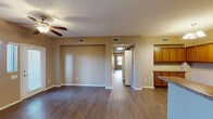 Located at 6885 W Lone Mountain Rd in Las Vegas, NV, this single-floor, 3-bedroom, 2-bathroom home offers a practical and comfortable layout designed for everyday living. Rich wood-look flooring flows throughout the main living areas, complemented by warm neutral-toned walls that create a cohesive and inviting ambiance.

The open living room is bathed in natural light from large windows fitted with vertical blinds, and features a ceiling fan along with a convenient built-in desk area. It connects seamlessly to the kitchen, which is well-appointed with warm wood cabinetry, granite-style countertops, stainless steel appliances including a gas range and built-in microwave, and an elegant pendant chandelier overhead.

The three bedrooms are generously sized, with the primary bedroom offering a comfortable retreat with closet access. All bedrooms continue the wood-look flooring and maintain the home's consistent neutral palette. The two bathrooms are finished with wood-toned vanities, granite-style countertops, and tub-shower combinations. A dedicated in-unit laundry room with wire shelving accommodates a full-size washer and dryer. The home is completed by a welcoming entrance and a hallway connecting all areas efficiently.