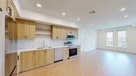 Located at 5050 Arrow Hwy in Montclair, CA, this thoughtfully designed 2-bedroom, 2-bathroom residence offers a clean, modern aesthetic throughout its single-floor layout. Light wood-tone flooring runs through the main living areas, lending warmth and continuity to the open-concept living and dining space, which is bathed in natural light and illuminated by recessed ceiling lights.

The kitchen is a standout feature, showcasing natural wood cabinetry, a herringbone-patterned tile backsplash, crisp white quartz countertops, open shelving, and a full suite of stainless steel appliances including a refrigerator, electric range, over-the-range microwave, and dishwasher. The layout flows seamlessly into the living and dining area, making it ideal for everyday living and entertaining.

Both bedrooms are carpeted and filled with natural light from large windows that offer neighborhood views. The primary bedroom is generously sized and provides comfortable proportions. Three closets, including a walk-in with built-in shelving and hanging rods, offer ample storage throughout. The bathrooms feature clean, white large-format tile, including a glass-enclosed walk-in shower. An in-unit laundry area adds everyday convenience to this well-appointed home.