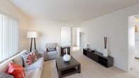 The A Model at 49 Oaklawn in Chula Vista is a thoughtfully laid-out single-floor residence that balances comfort and functionality. The living room serves as the heart of the home, featuring plush wall-to-wall carpeting, crisp white walls, and a large window dressed with vertical blinds that allows generous natural light to fill the space. The open layout provides ample room for seating and a media console, creating a welcoming area for relaxing or entertaining.

The kitchen is finished in a clean, all-white palette with abundant upper and lower cabinetry, a double-basin stainless steel sink, and light tile flooring. The generous counter space and bright natural light from a window make it a practical and pleasant workspace.

The bedrooms are carpeted and serene, each offering a calm retreat with neutral walls and vertical-blind windows that provide both light control and privacy. Sliding-door closets offer convenient built-in storage, and ceiling fans in select rooms enhance comfort year-round.

The bathroom is finished in white throughout, featuring a vanity with a mirrored medicine cabinet, globe-style vanity lighting, and a clean, minimalist aesthetic that keeps the space feeling fresh and functional. Overall, the A Model presents a well-organized, move-in-ready layout suited to everyday living.