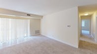 Located at 14207 Grand Pre Road in Silver Spring, Maryland, this single-floor residence offers a thoughtfully laid-out living space with a clean, neutral aesthetic throughout. The living area features light-toned carpeting, a sliding glass door with vertical blinds that invites natural light, and a programmable thermostat, creating a comfortable and functional environment.

The bedrooms are carpeted and finished with neutral walls and white baseboards. Natural light enters through windows with vertical blinds, and at least one bedroom features a walk-in closet with built-in shelving, providing generous storage. The rooms offer a calm, open feel well-suited for versatile use.

The kitchen is equipped with light wood cabinetry, laminate countertops, a black electric range, and a stainless steel over-the-range microwave, delivering a practical cooking space with modern appliances.

Two bathrooms serve the residence. One features white square tile surrounding a tub/shower combo with a handheld showerhead. The second bathroom includes warm taupe tile in the tub/shower surround, a wood-toned vanity with a light countertop, and durable tile flooring.

The doll's-eye view of the floor plan reveals a well-organized, open layout with clearly defined rooms and efficient use of space throughout the single floor.