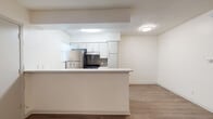 This single-story residence offers a well-organized layout that balances function and comfort throughout its living spaces. The kitchen serves as a central highlight, designed with white cabinetry, light quartz-style countertops, and a full suite of stainless steel appliances including a gas range, refrigerator, and dishwasher. A gray subway tile backsplash adds a modern accent, while a peninsula with an integrated sink creates a natural boundary between the kitchen and the adjoining living and dining areas. The living area features wood-look plank flooring that extends toward the entry, with large windows fitted with blinds allowing ample natural light throughout. Ceiling fans are present in multiple rooms, contributing to air circulation and comfort. The bedrooms are carpeted for warmth and comfort, with one bedroom featuring a distinctive arched window that enhances its character, along with access to a walk-in closet. The bathroom includes a soaking tub and shower combination with clean white tile surround and chrome fixtures. Textured ceilings are found throughout, and the overall neutral color palette lends the space a clean, move-in-ready aesthetic.