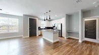 This well-designed single-story home offers three bedrooms, two bathrooms, and a functional layout that balances style with everyday practicality. A welcoming hallway with warm wood-look flooring and crisp white trim leads into the heart of the home — an open-concept kitchen and living area filled with natural light. The kitchen is a standout feature, showcasing white shaker cabinetry, dark tile backsplash, granite countertops, stainless steel appliances, and a central island with elegant pendant lighting above. The spacious living room extends from the kitchen, offering large windows, a ceiling fan, and a door to the outdoors. The bedrooms are comfortable and bright, featuring plush carpeting, ceiling fans, and windows that bring in natural light. The primary bedroom provides a generous retreat with ample space. Both bathrooms are finished with granite vanity tops, white cabinetry, wood-look flooring, and glass-enclosed showers. A dedicated laundry room with an in-unit washer and dryer adds convenience. Three closets provide ample storage throughout. Neutral gray walls, bold dark-paneled doors, and consistent flooring tie the home together with a cohesive, contemporary aesthetic.