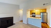 This single-floor residence offers a thoughtfully designed open-concept layout that connects the main living areas seamlessly. The living room is a welcoming space highlighted by a fireplace, soft carpet underfoot, and a sliding glass door fitted with vertical blinds that leads to an outdoor area, allowing natural light to fill the room. A secondary window further brightens the space with views of surrounding greenery.

The kitchen is well-appointed with warm honey-toned cabinetry, a classic white subway tile backsplash, granite countertops, and a full suite of stainless steel appliances including a refrigerator, range, and microwave. A peninsula with a double undermount sink serves as both a functional workspace and a casual dining area, and transitions into the living space via an open pass-through, enhancing the open feel. The kitchen features hardwood flooring, contrasting with the plush carpet found throughout the living and bedroom areas.

The bedroom is generously sized with a ceiling fan, large windows overlooking lush trees, and ample natural light. The bathroom includes a granite-topped vanity with warm wood cabinetry, a tub-shower combination with brushed nickel fixtures, and hardwood flooring, completing this well-balanced and comfortable residence.