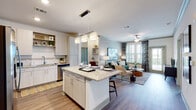 This well-designed single-floor residence offers a cohesive blend of modern finishes and functional living spaces. The open-concept layout seamlessly connects the kitchen, dining, and living areas, creating a bright and welcoming atmosphere enhanced by natural light from large windows adorned with stylish drape-and-blind combinations.

The kitchen is a standout feature, equipped with stainless steel appliances including a refrigerator with ice maker, range, microwave, and dishwasher. Light wood-tone cabinetry, granite countertops, a tile backsplash, and open display shelving combine practicality with contemporary style. A central island with bar seating serves as both a prep area and casual dining space, illuminated by modern pendant lighting.

The living area is generously proportioned, featuring crown molding, a ceiling fan, and views to the outdoors through large windows. Wood-style flooring runs throughout the main living spaces, transitioning to plush carpet in the bedrooms.

Both bedrooms are comfortably sized with ceiling fans and large windows offering outdoor views, including what appears to be a scenic waterfront vista. The bathrooms are finished with granite vanity countertops and wood-style flooring. One bathroom features a tiled soaking tub and shower combination, while the other offers a clean, minimalist vanity layout. Storage and built-in shelving add to the overall functionality of this thoughtfully designed residence.