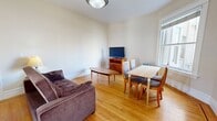 Located at 641 O'Farrell Street in San Francisco's Tenderloin/Polk Gulch neighborhood, this two-bedroom, one-bathroom apartment offers a practical and comfortable urban layout across a single floor. Warm hardwood flooring runs throughout the living areas and bedrooms, creating a cohesive and inviting atmosphere.

The combined living and dining room is a bright, open space anchored by large windows that allow natural light to pour in and offer views of the surrounding San Francisco cityscape. The living area provides ample room for seating, while the dining space comfortably accommodates a full table and chairs.

The kitchen features rich wood cabinetry, white countertops, a gas range, and a full-size refrigerator. A window above the counter provides additional natural light, and dark tile flooring adds contrast to the warm wood tones.

The spacious primary bedroom is a standout feature, boasting a classic bay window that floods the room with natural light and frames city views. Built-in shelving and multiple closet doors offer generous storage. The second bedroom is comfortably sized with continued hardwood flooring and neutral tones.

The bathroom is finished with classic white tile accented by a bold navy border and a mosaic tile detail, lending it a clean, timeless character. A window provides natural ventilation and light.