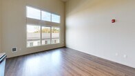 Located at 10715 NE 37th Ct in Kirkland, WA, this efficiently designed studio unit offers a well-organized single-floor layout that maximizes every square foot. The combined kitchen and living area serves as the heart of the space, highlighted by impressively tall ceilings that create a strong sense of openness and volume. Large windows along the living area wall flood the space with abundant natural light while offering views of the surrounding neighborhood.

The kitchen is outfitted with a full suite of stainless steel appliances, including a refrigerator, electric range, microwave, and dishwasher. Rich dark-toned cabinetry extends to the upper walls, providing generous storage, and is complemented by granite-style countertops that add a refined touch. Hardwood-style flooring runs consistently throughout the unit, lending warmth and visual continuity.

The bathroom features a dark espresso vanity with a granite countertop, a large mirror with overhead lighting, a shower/tub combination, and wood-look tile flooring. Accessibility-conscious grab bars are also present. The unit further includes two closets for ample storage, a dedicated laundry area, and a well-lit entry corridor equipped with an electrical panel. The overall aesthetic is clean, modern, and functional.